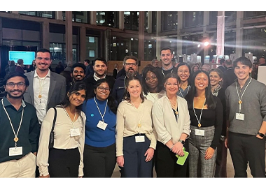 a group of students and professors stand smiling at the camera